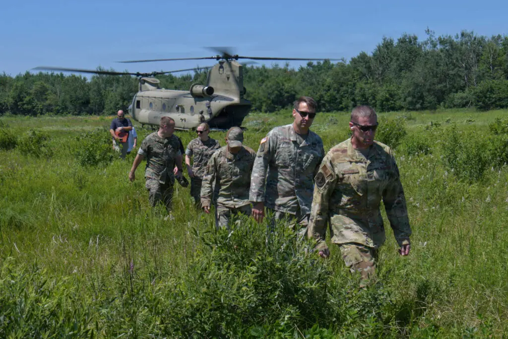 Military and civilians walking away from a Chinook helicopter