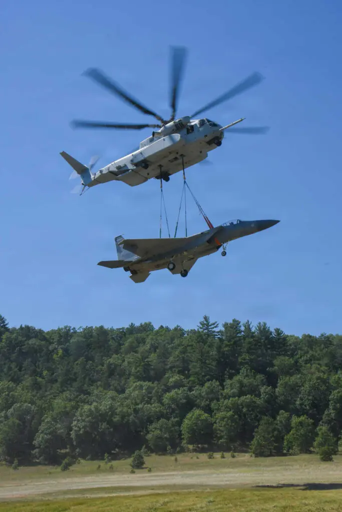 a helicopter lifting a F-15