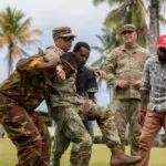 Soldiers helping train how to carry someone