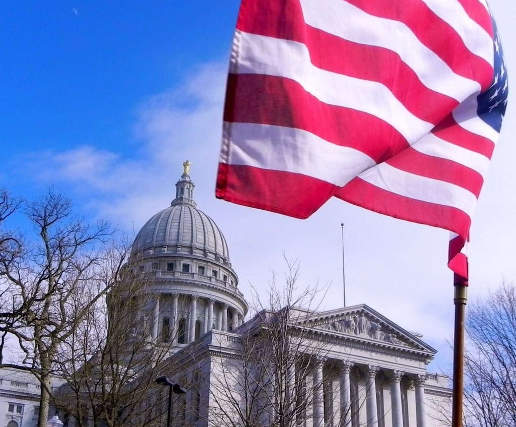 A flag flying next to the Wisconsin State Capitol