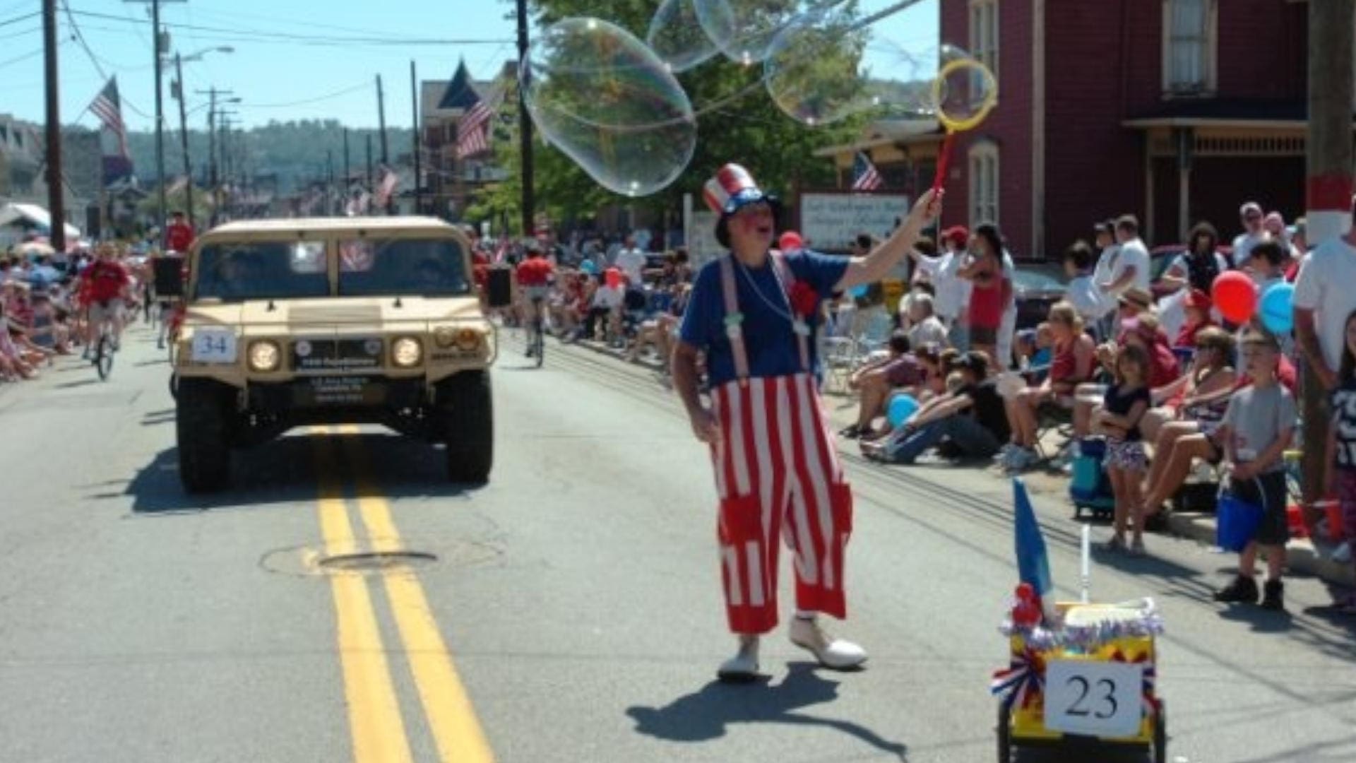 A vehicle in a parade with lots of people watching from the sides of the road