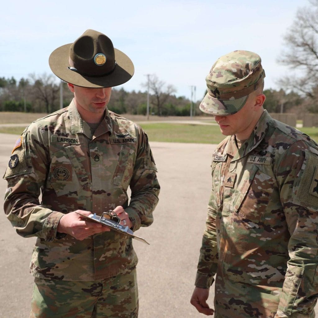 Soldiers looking at a clipboard while working on a project