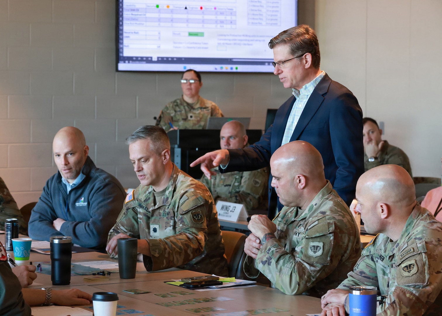 Personnel taking part in wargaming around a table
