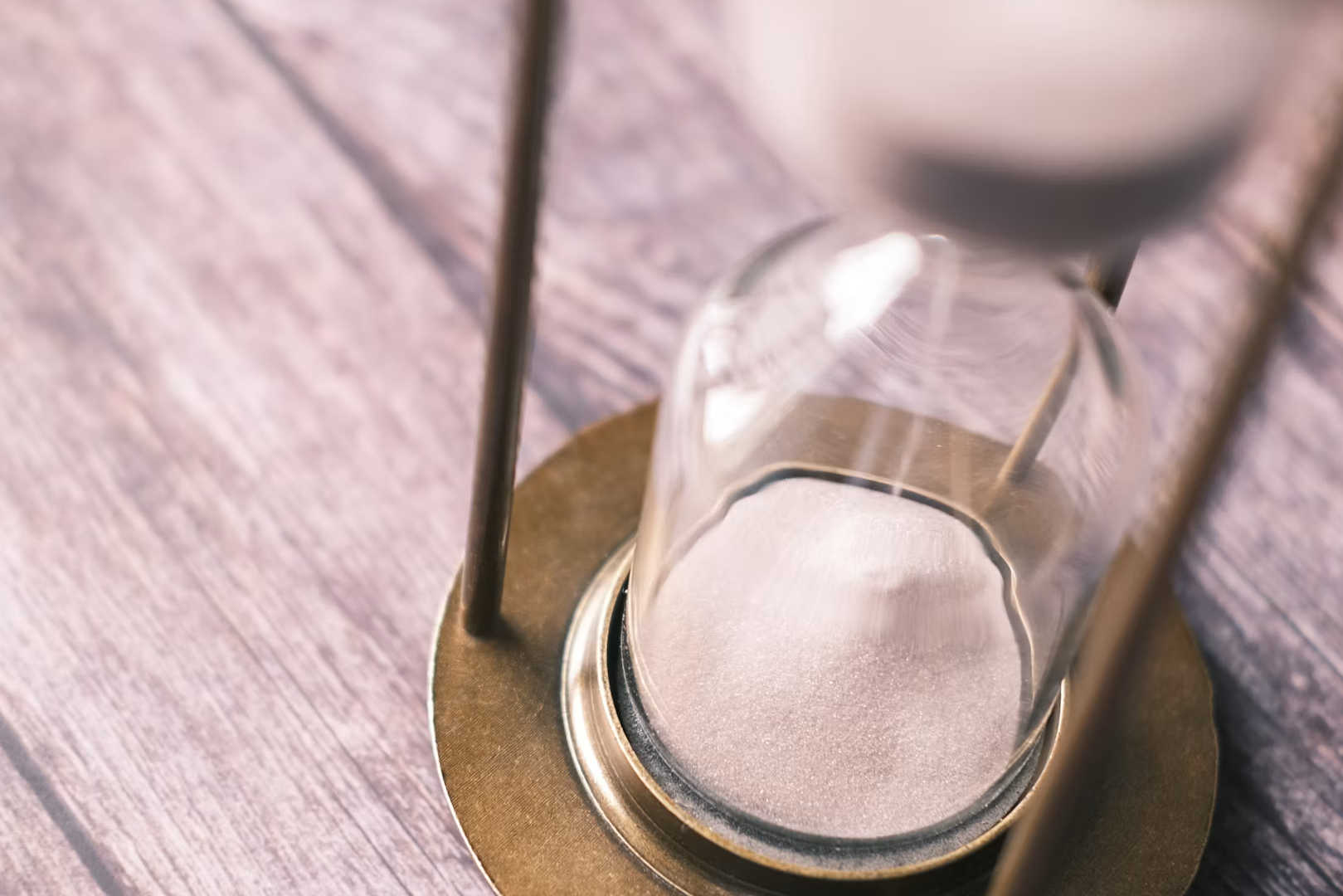 An hour glass sitting on a table half full of sand