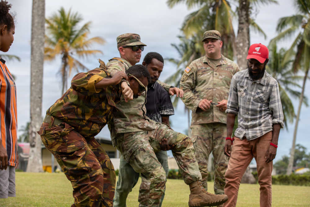 Soldiers helping train how to carry someone