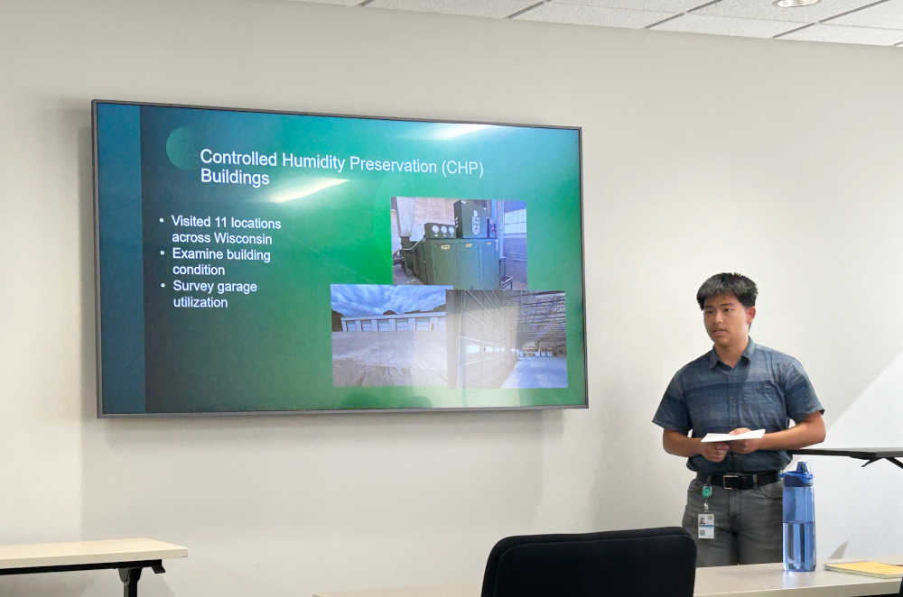 A presentation in front of of a screen talking about Controlled Humidity Preservation Buildings