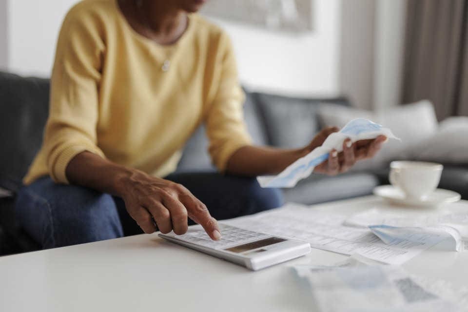 A person using a calculator to do math while looking at receipts.